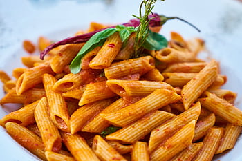 Savor the flavors of Italian cuisine with this close-up of tasty penne pasta in tomato sauce. HD wallpaper