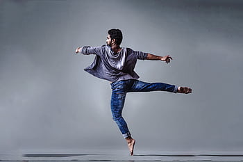A male dancer executing a high jump in a studio setting, showcasing grace and agility. HD wallpaper