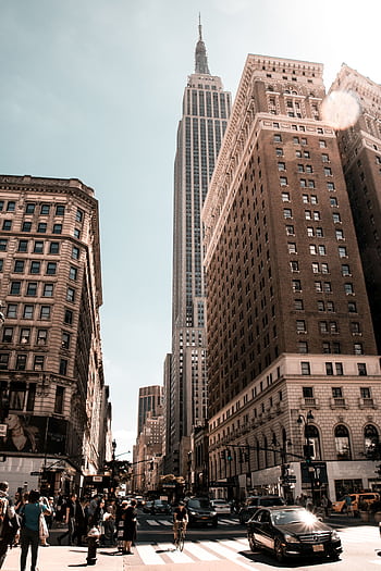 Bustling city life with iconic skyscraper under clear sky. HD phone wallpaper