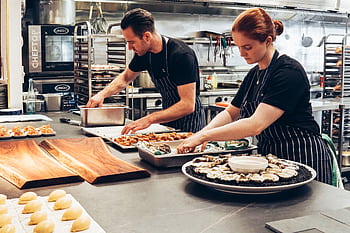 Two chefs working together in a professional kitchen, preparing gourmet dishes with precision. HD wallpaper