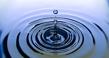 A stunning close-up of a water droplet creating ripples on a smooth water surface, capturing nature's simplicity. HD wallpaper