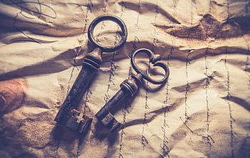 Vintage iron keys resting on crumpled, handwritten paper with a rustic texture. HD wallpaper