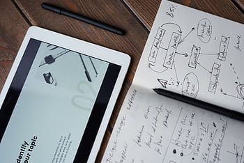 Digital and handwritten brainstorming tools on a wooden desk, ideal for business and study contexts. HD wallpaper