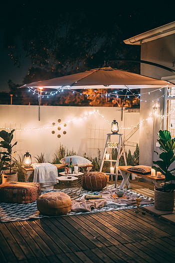 Charming outdoor patio scene with cozy seating and warm lighting at night. HD phone wallpaper
