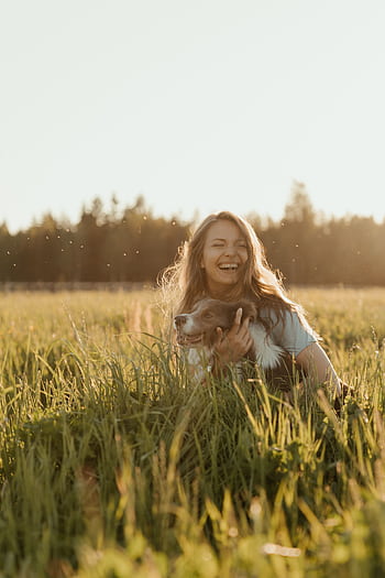 Smiling woman with her pet dog in a sunlit meadow during summer. HD phone wallpaper