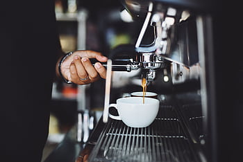 Close-up of a barista preparing espresso in a café using a machine HD wallpaper