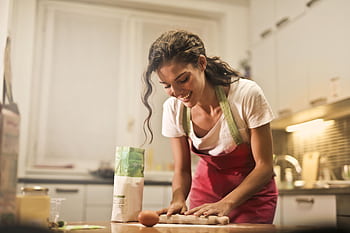 Smiling woman making dough at home, enjoying the baking process. HD wallpaper