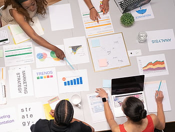 Top view of a team collaborating on marketing strategy and analysis papers. HD wallpaper