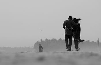 A romantic black and white shot of a couple walking arm in arm on a misty beach in Kochi, India. HD wallpaper