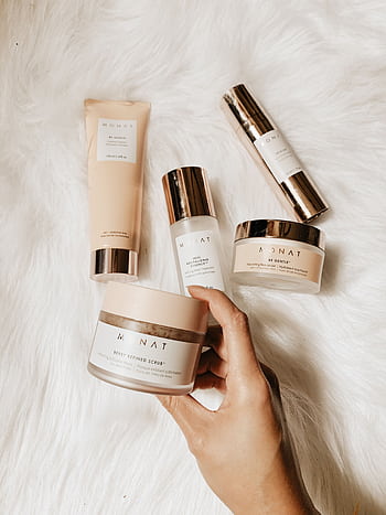 Collection of luxury skincare products arranged on a warm, soft fur surface for a chic presentation. HD phone wallpaper
