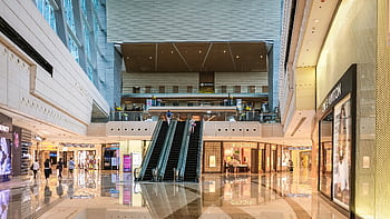 Modern shopping mall interior with escalators and luxury stores in Hong Kong. HD wallpaper