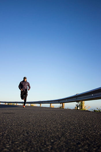 An athletic man jogging on an open road with a clear blue sky in Cape Town, South Africa. HD phone wallpaper