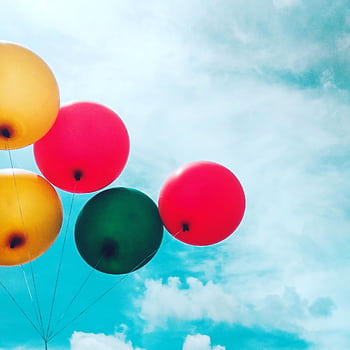 Colorful balloons float joyfully against a bright blue sky with scattered clouds. HD phone wallpaper