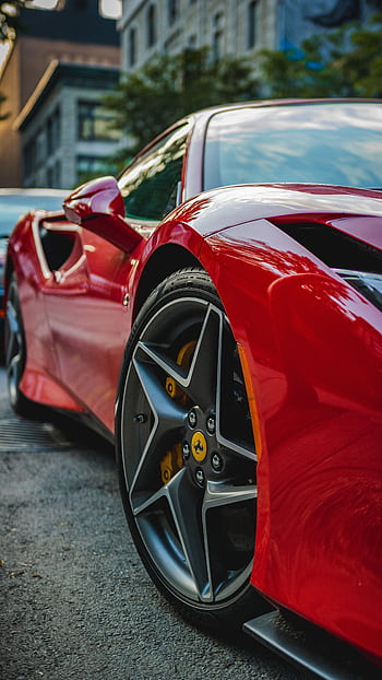 Close-up of a luxurious red sports car parked in a bustling city street. HD phone wallpaper