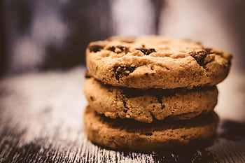 A macro shot of freshly baked stacked chocolate chip cookies creates a cozy dessert vibe. HD wallpaper