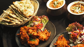 A delicious Indian food spread featuring curries, naan, and colorful salads, perfect for dinner. HD wallpaper