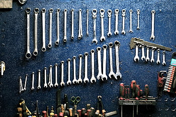 Neatly arranged wrenches and tools on a workshop wall, ideal for mechanics. HD wallpaper