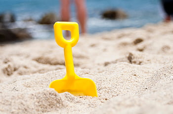 Bright yellow shovel in sandy beach setting, perfect summer fun ry. HD wallpaper