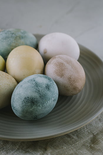 A close-up of naturally painted Easter eggs on a rustic ceramic plate, ideal for festive decorations. HD phone wallpaper