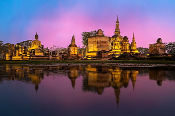 Beautiful sunset view of Wat Mahathat temple in Sukhothai, Thailand, reflecting in the surrounding water. HD wallpaper
