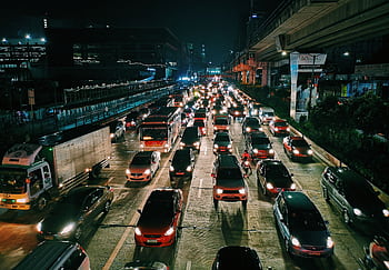 A bustling urban highway filled with cars and buses at night, showcasing city life and transportation. HD wallpaper