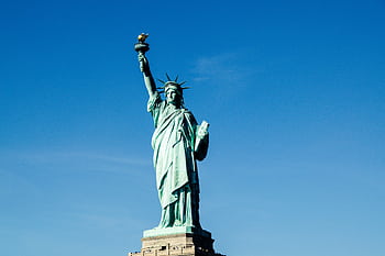 Iconic Statue of Liberty with vibrant blue sky backdrop, symbolizing dom and hope. HD wallpaper
