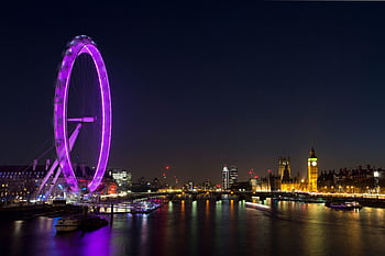 Night view of the illuminated London Eye and Big Ben across the Thames River, showcasing London's vibrant skyline. HD wallpaper