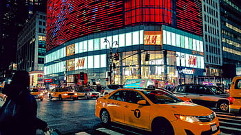 Dynamic night scene in Times Square with traffic and illuminated buildings. HD wallpaper