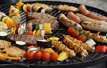 A vibrant assortment of grilled meats, sausages, and vegetables on a barbecue grill. HD wallpaper