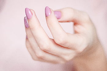 A close-up of a woman's hand showing a stylish pink and glittery manicure. HD wallpaper