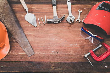 Flat lay of various workshop tools on a rustic wooden table, showcasing DIY essentials. HD wallpaper