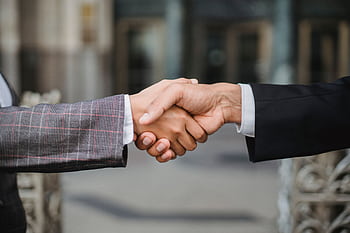 A close-up of two businesspeople shaking hands, symbolizing cooperation and partnership. HD wallpaper