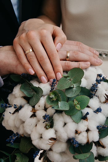 Close-up of couple's hands with gold wedding bands over a floral bouquet. HD phone wallpaper