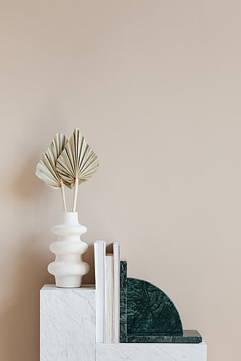 A contemporary beige room setup featuring a unique ceramic vase and stylish bookshelf. HD phone wallpaper