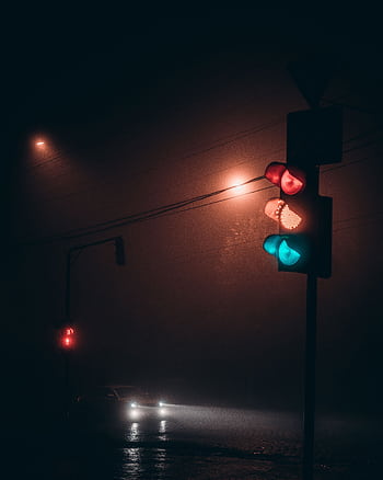 A misty night scene featuring illuminated traffic lights and a car on a city street. HD phone wallpaper