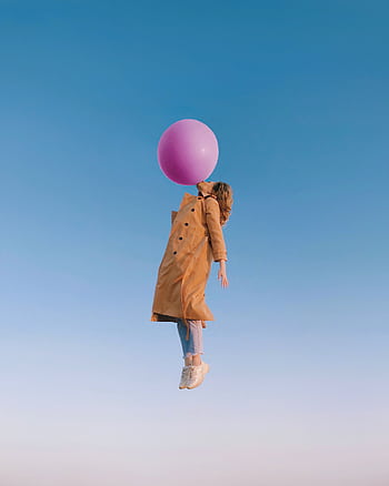 A woman in a trench coat seems to float with a balloon against a clear blue sky, expressing dom and joy. HD phone wallpaper
