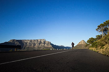 Man jogging along a scenic road with Table Mountain view in Cape Town. HD wallpaper