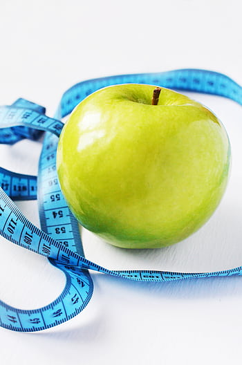 A fresh green apple surrounded by a blue measuring tape on a white background, symbolizing health and diet. HD phone wallpaper