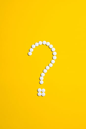White pills arranged in a question mark shape on a bright yellow background, symbolizing medical queries. HD phone wallpaper