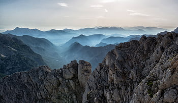 Capture of a tranquil mountain range at dawn with misty valleys and rocky peaks. HD wallpaper