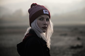 Elegant portrait of a woman in a beanie, set against a foggy and mysterious outdoor backdrop. HD wallpaper