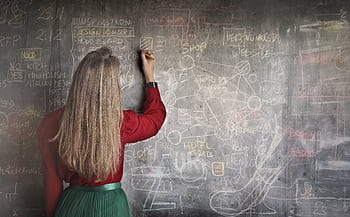 A woman writing and planning on a chalkboard, showcasing creative strategies and concepts. HD wallpaper