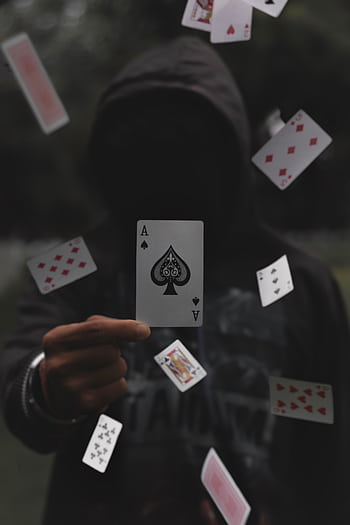 Enigmatic hooded figure with playing cards floating in mid-air, focusing on the ace of spades. HD phone wallpaper