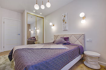 Elegant bedroom with purple decor, modern lighting, and mirror wardrobe. HD wallpaper