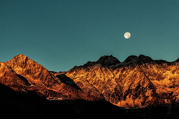 Breathtaking view of mountains with a full moon at twilight, capturing nature's beauty. HD wallpaper