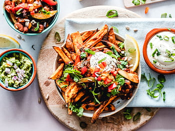 A vibrant platter of savory sweet potato fries with fresh toppings, perfect for a tasty snack. HD wallpaper