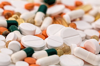 Close-up of various pills and capsules in different colors and sizes, ideal for healthcare-related content. HD wallpaper