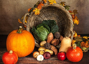 A rustic cornucopia overflowing with fresh autumn vegetables, symbolizing abundance and harvest. HD wallpaper
