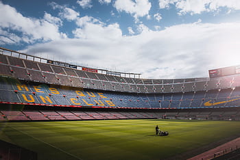 A vibrant football stadium with a well-maintained grass field under a bright sky, showcasing its iconic architecture. HD wallpaper