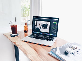 A cozy home office setup featuring a laptop and iced coffee on a wooden desk. HD wallpaper